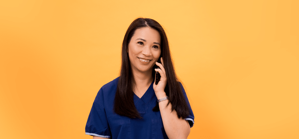 Clinician wearing scrubs holds phone to her ear